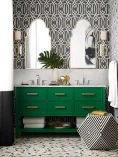 a bathroom with black and white wallpaper, green cabinetry, gold accents and mirrors