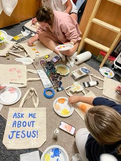 children are sitting on the floor painting with paper plates and crayons in front of them