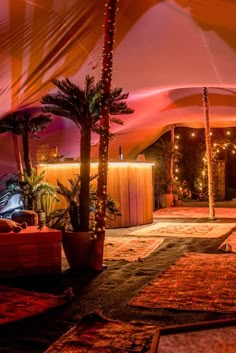 the inside of a tent is lit up with lights and palm trees