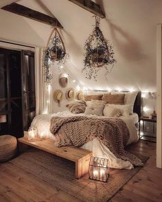 a bed with pillows, blankets and lights in a room that has wood floors and white walls