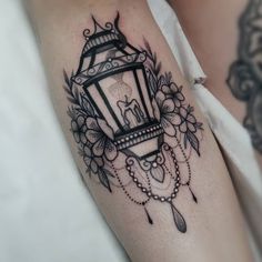 a woman's arm with a lantern and flowers tattoo on the left side of her body