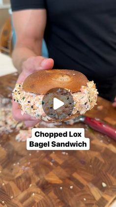 a person is holding a bagel sandwich in their hand with the text, chopped lox bagel sandwich