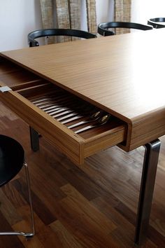 a wooden table with two chairs and a drawer underneath it that is open on the floor