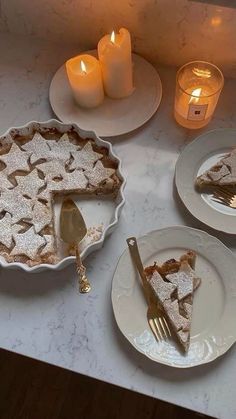 a table topped with plates covered in pie next to candles