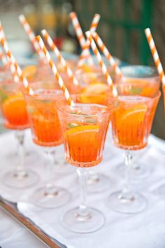 small glasses filled with orange juice and straws sitting on a tray, ready to be served