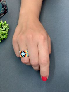 a woman's hand with a colorful ring on her finger and broccoli in the background