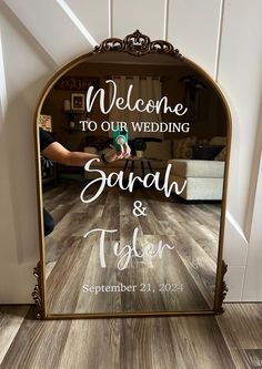 a mirror with the words welcome to our wedding sara and tyler on it in front of a wooden floor