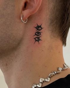 a man's neck with an evil eye tattoo on his left side behind the ear