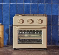 a toaster oven sitting on top of a counter next to a blue tiled wall