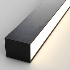 an illuminated black rectangular object on a white surface