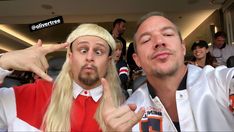 two men with long blonde hair are posing for the camera in front of an audience