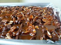 a pan filled with chocolate and nuts on top of aluminum foil covered in caramel