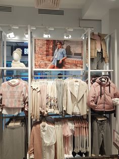 a clothing store display with clothes on racks and mannequins in the background