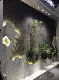 a large wall with plants on it in a room that is decorated with white and black walls