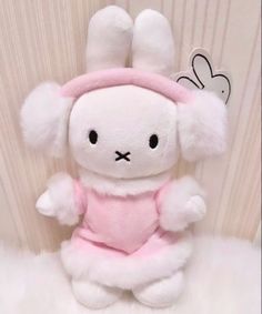 a white stuffed rabbit wearing a pink dress