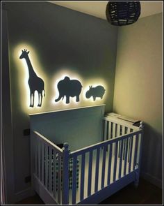 a baby's crib with some animals on the wall and lights above it