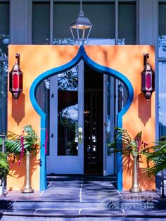 an entrance to a brightly colored building with potted plants