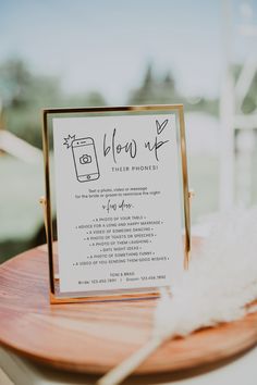 a wooden table topped with a sign and a feather on top of it's stand