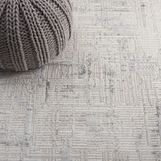 a ball of yarn sitting on top of a rug next to a gray and white carpet