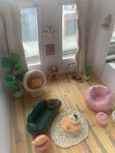 a doll house with furniture and accessories on the floor in front of two large windows