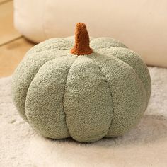 a green pumpkin sitting on top of a white rug