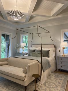 a bedroom with a four poster bed and white furniture in the corner, along with a chandelier hanging from the ceiling