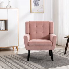 a pink chair sitting on top of a rug in a living room next to a book shelf