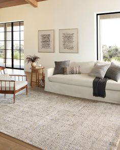 a living room filled with furniture and a white couch next to a large window on top of a hard wood floor