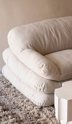 three pillows stacked on top of each other in front of a white wall and carpet