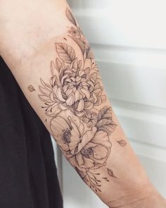 a woman's arm with flowers and leaves tattooed on the left side of her arm