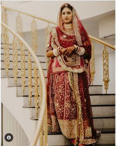 a woman in a red and gold bridal gown standing on the stairs with her hand on her hip