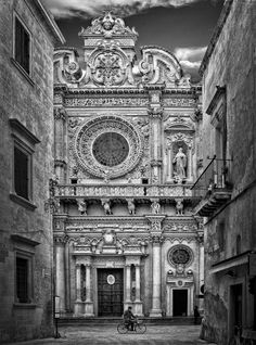 a black and white photo of an old building with a bicycle parked in front of it