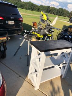 a motorcycle parked next to a table on the back of a car in a parking lot