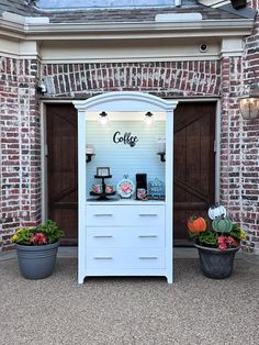 a coffee shop with two potted plants in front of the store's entrance