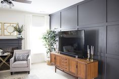 a living room with black walls and a flat screen tv sitting on top of a wooden entertainment center