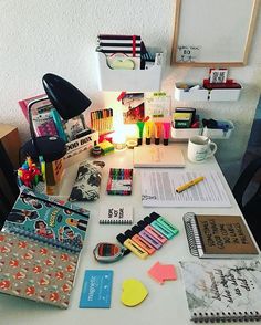 the desk is full of school supplies, books, pens and notebooks on it