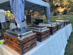 there are many wooden boxes on the table under the awning at this outdoor event