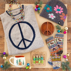 a peace sign sweater, hat, and other items laid out on a wooden table