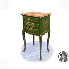 an old fashioned green and gold painted table with drawers on the bottom, next to a black and white photo