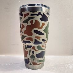 a camo print tumbler cup sitting on top of a white countertop next to a wall