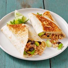 a white plate topped with two burritos on top of a blue wooden table