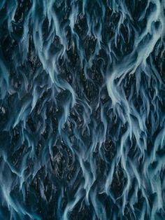 an aerial view of the water and rocks in the ocean, with blue waves coming from them