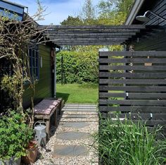 an outdoor area with benches and plants in the foreground, next to a house