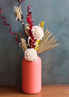 a vase filled with flowers on top of a wooden table next to a blue wall