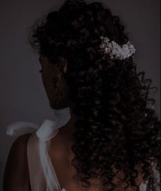 the back of a woman's head with curly hair and a flower in her hair