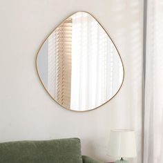 a living room with a green couch and a round mirror on the wall