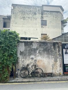 a bike parked next to a building with graffiti on the wall and bushes growing up against it