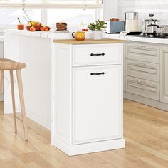 a white kitchen with an island in the middle and wooden floors on one side, two stools at the other end