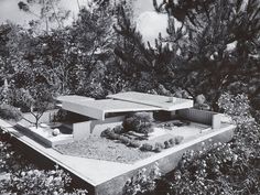 an old black and white photo of a house in the middle of some bushes with trees around it