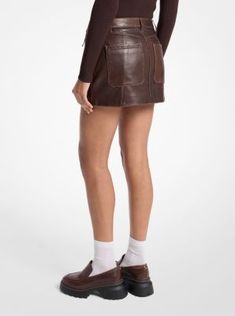 This moto-inspired skirt is made from supple leather with a faded finish that lends it a vintage touch. Slant pockets and tonal stitching add to its biker feel. Counter the mini length with combat boots. Brown Leather Skirt, Faux Leather Mini Skirt, Leather Mini Skirt, Michael Kors Collection, Leather Mini Skirts, Colby, Charcoal Color, Denim Mini Skirt, Leather Mini